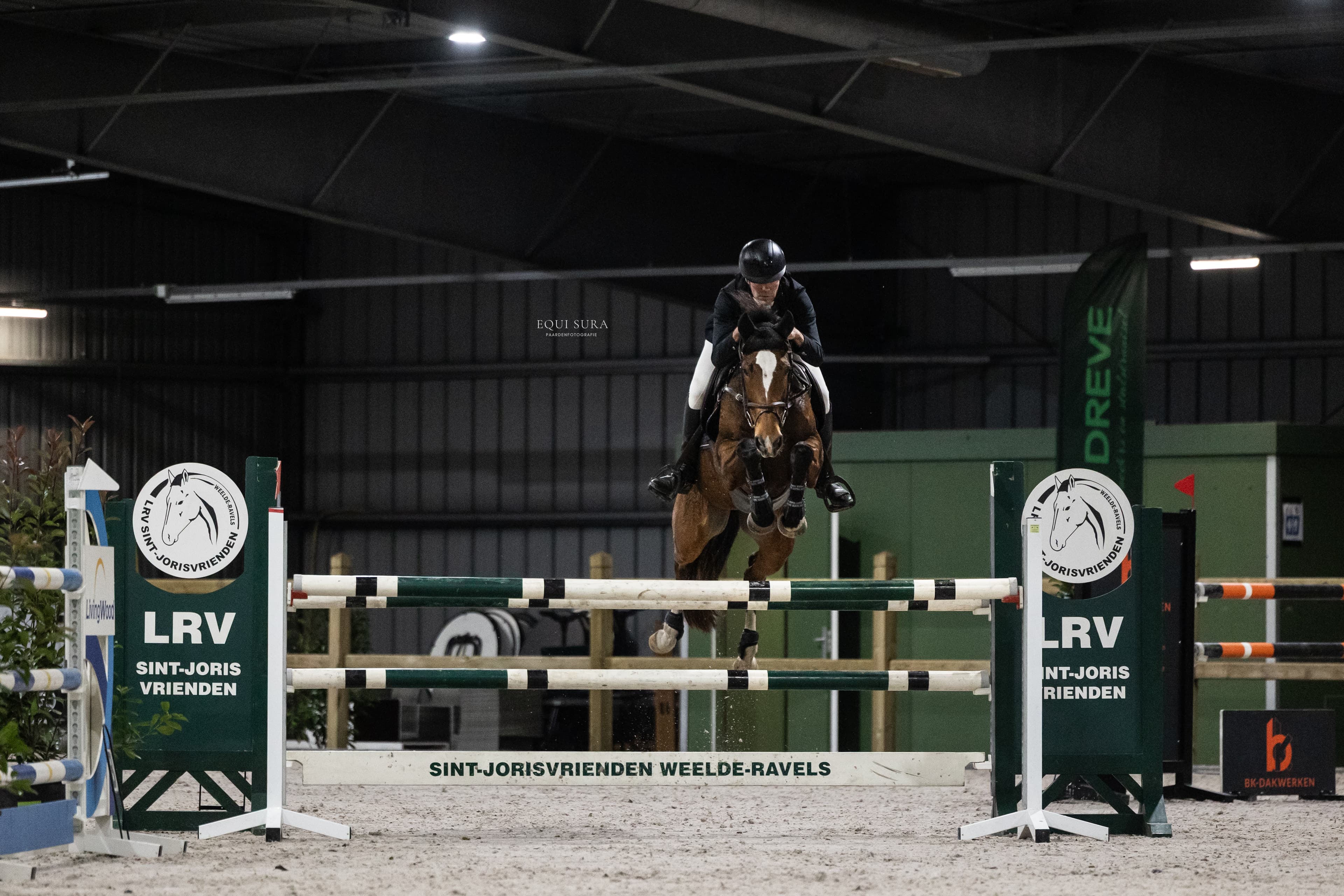 Picture of a man jumping over a barrier on a horse